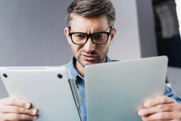Sceptische Reparateur Kijkt Naar Beschadigde Laptop Wazige Voorgrond — Stockfoto