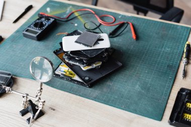 İş yerinde tornavida, büyüteç ve çoklu metre ile parçalanmış cep telefonlarının yüksek açılı görüntüsü