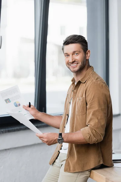 Lächelnder Geschäftsmann Mit Papierblättern Der Die Kamera Blickt Während Sich — Stockfoto