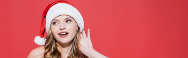Mutlu genç bir kadın Noel Baba şapkasını düzeltiyor ve kırmızıyı dinliyor. 