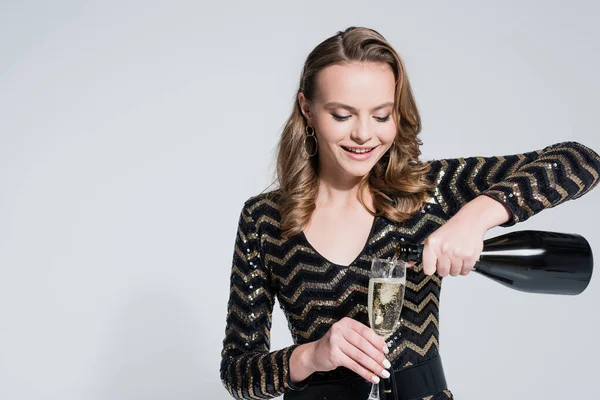 Happy Young Woman Holding Glass While Pouring Champagne Bottle Isolated — Stock Photo, Image