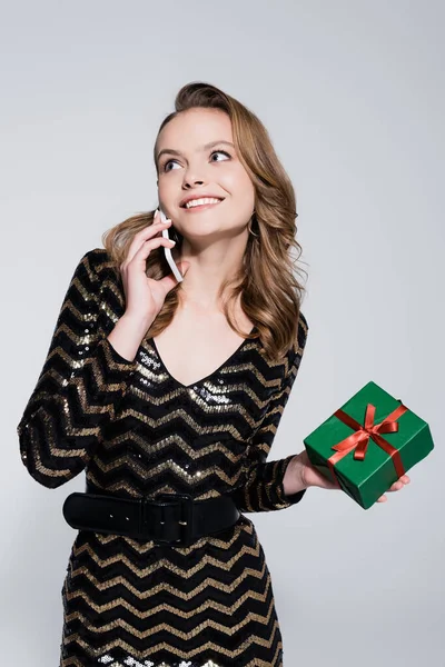 Glimlachende Jonge Vrouw Met Kerst Cadeau Praten Smartphone Geïsoleerd Grijs — Stockfoto