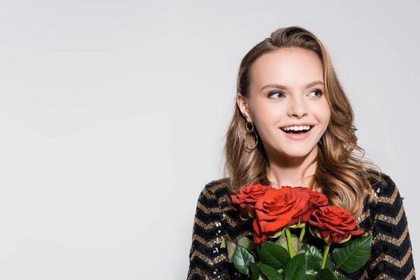 excited young woman holding bouquet of red roses isolated on grey