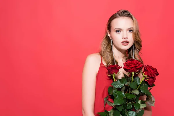 Νεαρή Γυναίκα Κρατώντας Τριαντάφυλλα Και Κοιτάζοντας Την Κάμερα Στο Κόκκινο — Φωτογραφία Αρχείου