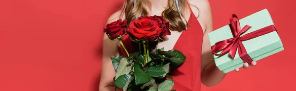 cropped view of woman holding roses and gift box on red, banner