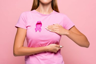 Göğüs kanseri olan genç bir kadının göğüslerine dokunan pembe kurdeleli bir kurdele görüntüsü. 