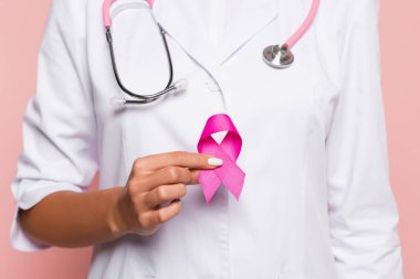 Cropped view of doctor in white coat holding pink ribbon of breast cancer awareness isolated on pink clipart