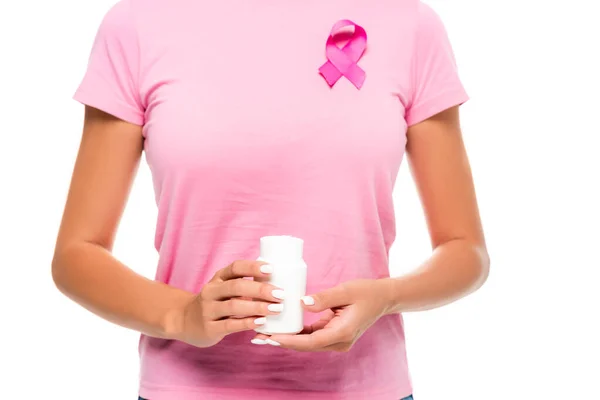 白い上に隔離された背景に乳がんの意識のピンクのシンボルを身に着けている間丸薬で瓶を保持している女性の作物ビュー — ストック写真