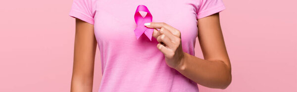 Обрезанный вид молодой женщины, держащей рак молочной железы знак осведомленности изолированы на розовый, баннер 