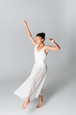 Beyaz arka planda dans eden çıplak ayaklı Afro-Amerikan balerin.