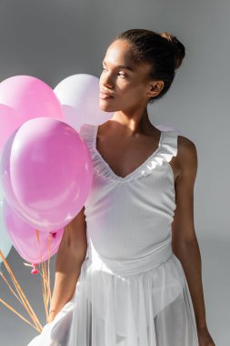 Beyaz arka planda balonlar olan zarif bir Afrikalı Amerikalı balerin.