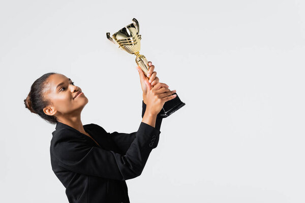 smiling african american businesswoman with golden cup isolated on grey