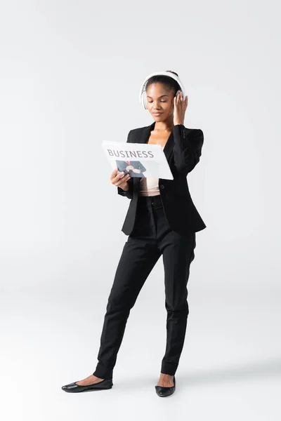 Mujer Negocios Afroamericana Escuchando Música Auriculares Leyendo Periódico Negocios Aislado —  Fotos de Stock