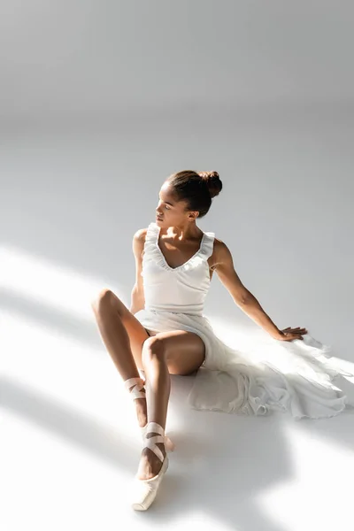 Elegante Bailarina Afroamericana Vestido Sentado Suelo Sobre Fondo Blanco —  Fotos de Stock