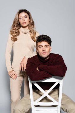 Balıkçı yaka kazaklı sıradan bir çift gri üzerine izole edilmiş poz veriyor.