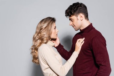 Balıkçı yaka kazaklı, gri kazaklı sıradan bir çiftin yan görüntüsü.