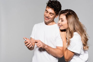 Beyaz tişörtlü, akıllı telefonlu, gri tişörtlü mutlu çift.