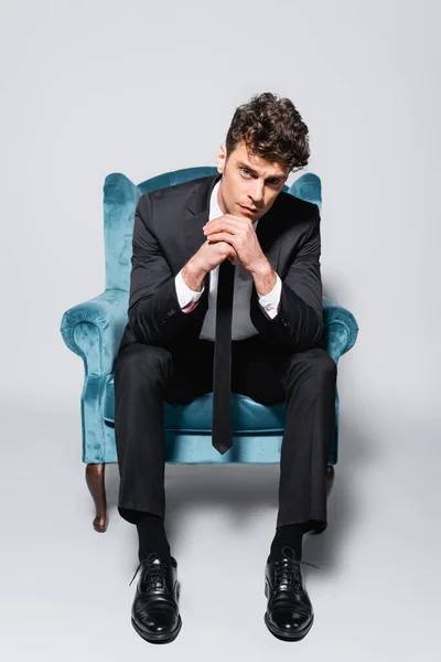 Elegante Hombre Traje Sentado Sillón Terciopelo Aislado Gris — Foto de Stock