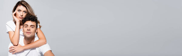 young couple in white t-shirts embracing isolated on grey, banner