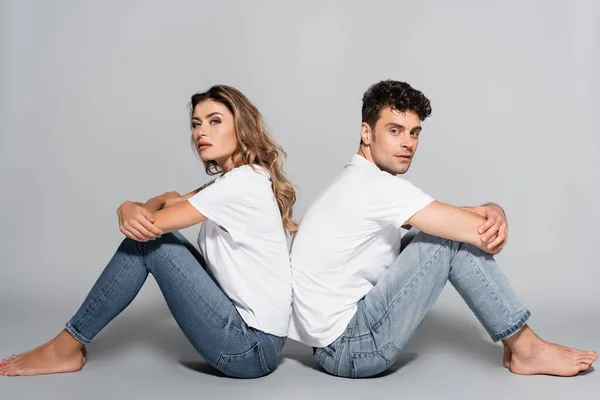 Giovane Coppia Shirt Bianche Jeans Posa Schiena Schiena Isolata Grigio — Foto Stock