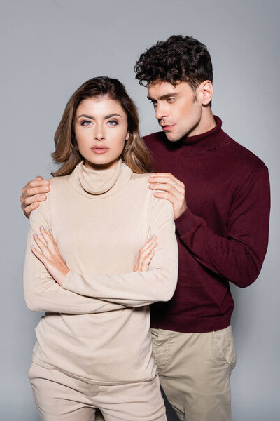 casual young couple in jumpers posing isolated on grey