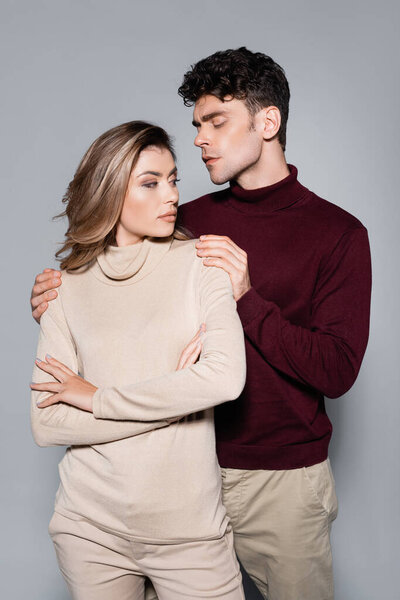 casual young couple in jumpers posing isolated on grey