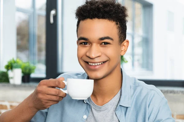 若いアフリカ系アメリカ人の男性がコーヒーを飲みながら笑顔で — ストック写真