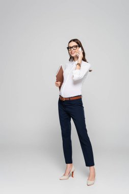 Gözlüklü, akıllı telefondan konuşan, gri gözlüklü genç hamile iş kadını.