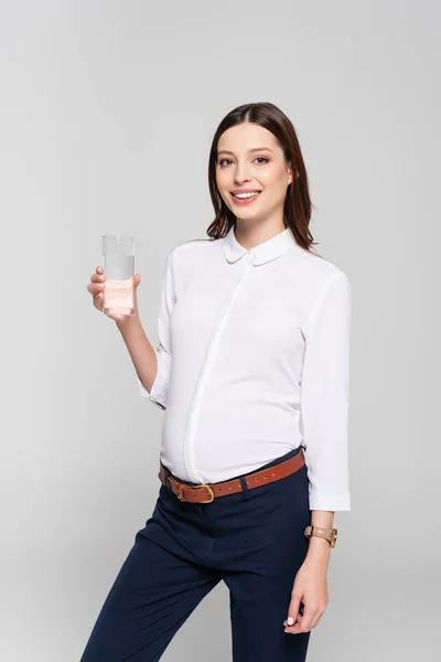 Lächelnde Junge Schwangere Geschäftsfrau Mit Glas Wasser Auf Grau Isoliert — Stockfoto