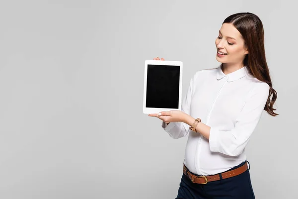 年轻的怀孕女商人笑着展示用灰色隔离的数码平板电脑 — 图库照片