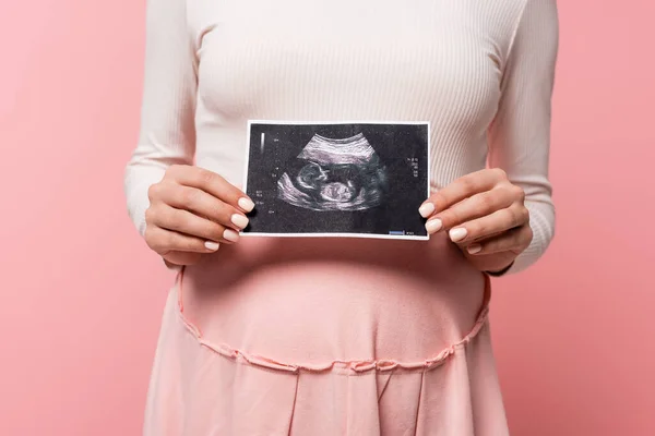 ピンクに隔離された超音波スキャンを保持している妊婦のクロップドビュー — ストック写真