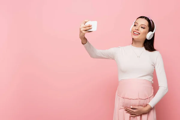 Felice Giovane Bella Donna Incinta Cuffia Utilizzando Smartphone Isolato Rosa — Foto Stock