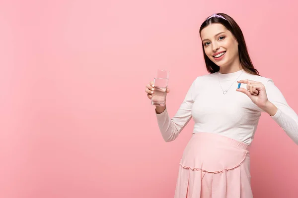 Šťastný Mladý Pěkný Těhotná Žena Sklenicí Vody Pilulky Izolované Růžové — Stock fotografie