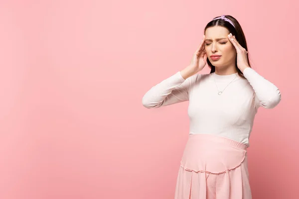 ピンク色に隔離された頭痛に苦しむ若い妊娠中の女性 — ストック写真
