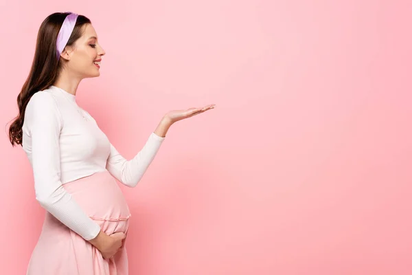 Gelukkig Jong Vrij Zwangere Vrouw Wijzend Met Hand Geïsoleerd Roze — Stockfoto