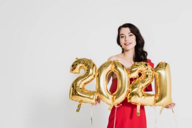 Gülen kadın elinde 2021 şeklinde altın balonlar tutuyor gri üzerinde izole edilmiş numaralar. 