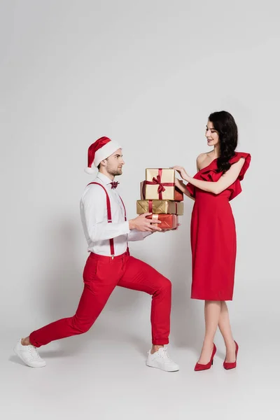 Man Santa Hatt Håller Gåvor Nära Leende Kvinna Röd Klänning — Stockfoto