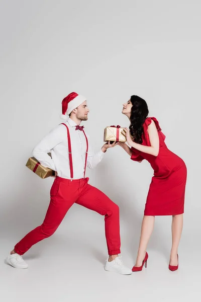 Homem Santa Chapéu Dando Presente Mulher Morena Vestido Vermelho Saltos — Fotografia de Stock