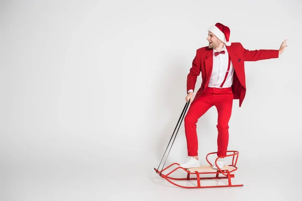 Cheerful Man Santa Hat Red Suit Standing Sleigh Grey Background — Stock Photo, Image