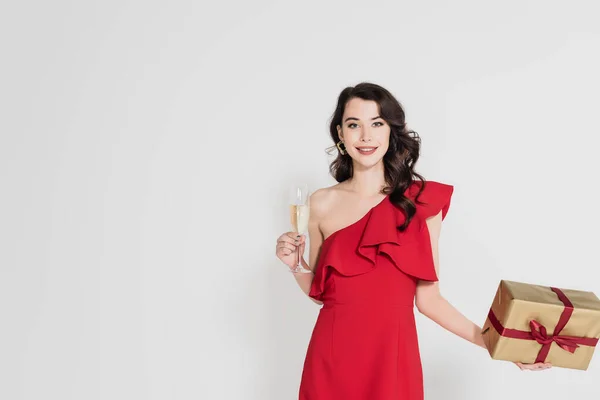 Leende Kvinna Röd Klänning Håller Glas Champagne Och Gåva Isolerad — Stockfoto