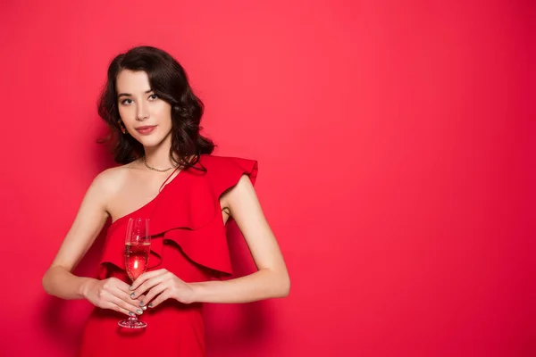 Brünette Frau Kleid Mit Einem Glas Champagner Auf Rotem Hintergrund — Stockfoto