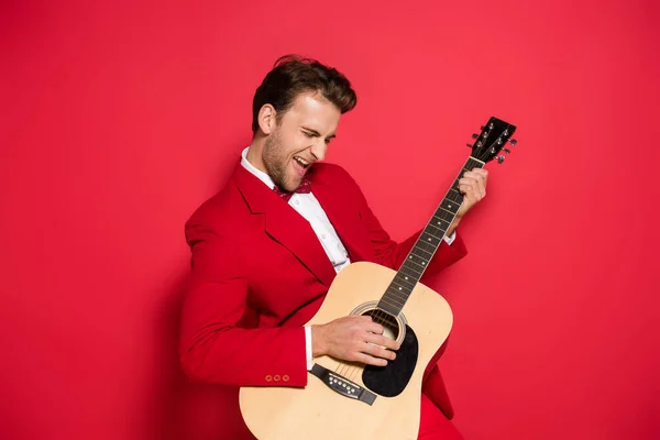 Homem Excitado Terno Vermelho Tocando Guitarra Acústica Fundo Vermelho — Fotografia de Stock