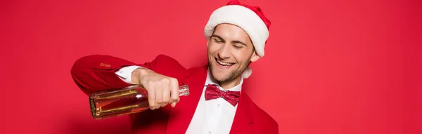 Cheerful Man Santa Hat Holding Bottle Champagne Red Background Banner — Stock Photo, Image