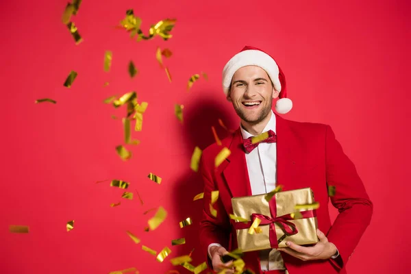 Elegante Hombre Sombrero Santa Sonriendo Cámara Mientras Sostiene Presente Cerca — Foto de Stock