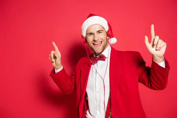 Man Santa Hatt Och Hörlurar Pekar Med Fingrar Röd Bakgrund — Stockfoto