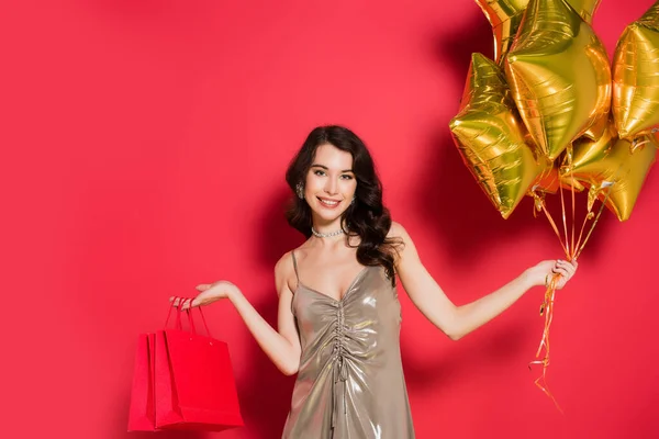 Mujer Sonriente Sosteniendo Globos Bolsas Compras Sobre Fondo Rojo — Foto de Stock