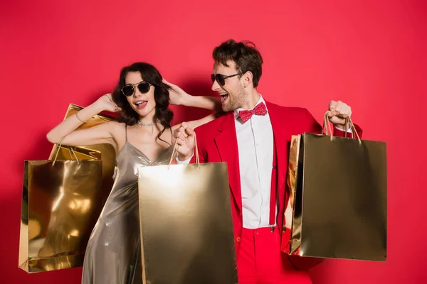 Stylish Man Sunglasses Holding Shopping Bags Cheerful Girlfriend Red Background — Stock Photo, Image