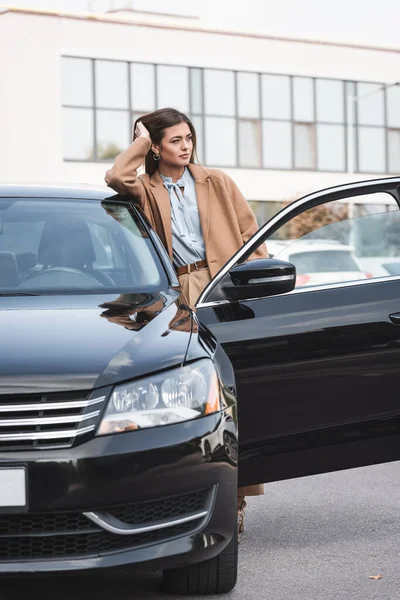 Dreamy Woman Stylish Trench Coat Leaning Black Car Looking Away — Stock Photo, Image