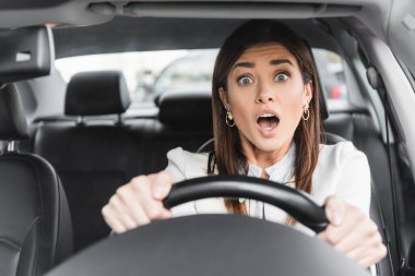 frightened woman screaming while driving car on blurred foreground clipart