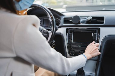 Tıbbi maskeli bir kadının bulanık ön plandaki kontrol panelini ayarlarken görüntüsü...
